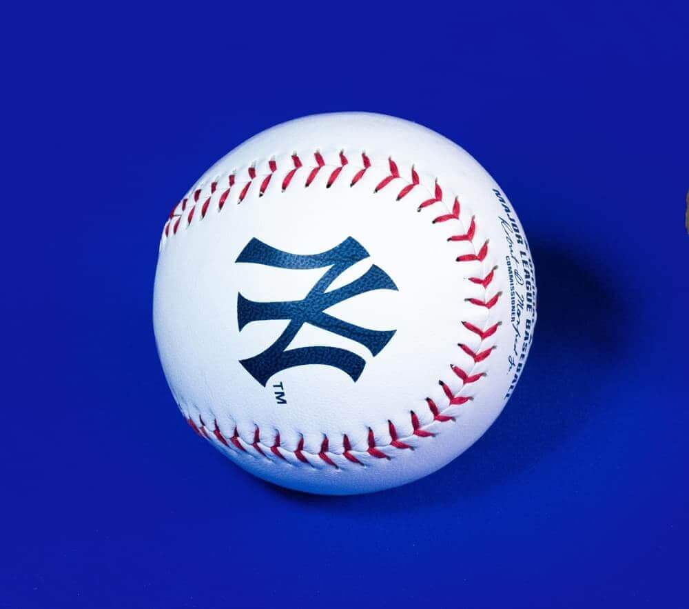 New York Yankees baseball with iconic logo on a blue background, symbolizing team spirit and heritage.