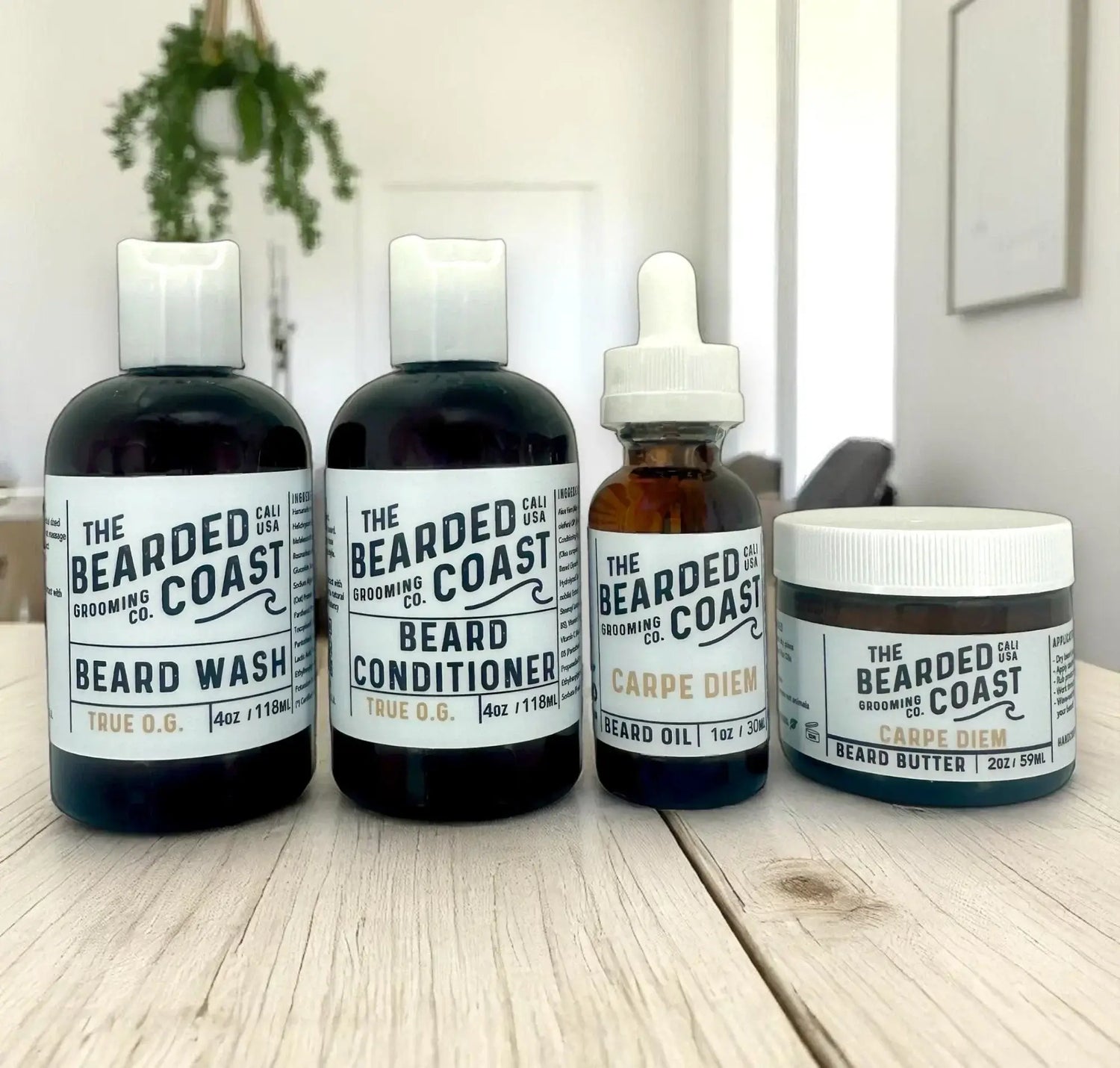 Beard wash, conditioner, oil, and butter from Bearded Coast displayed on a light wood table in natural light