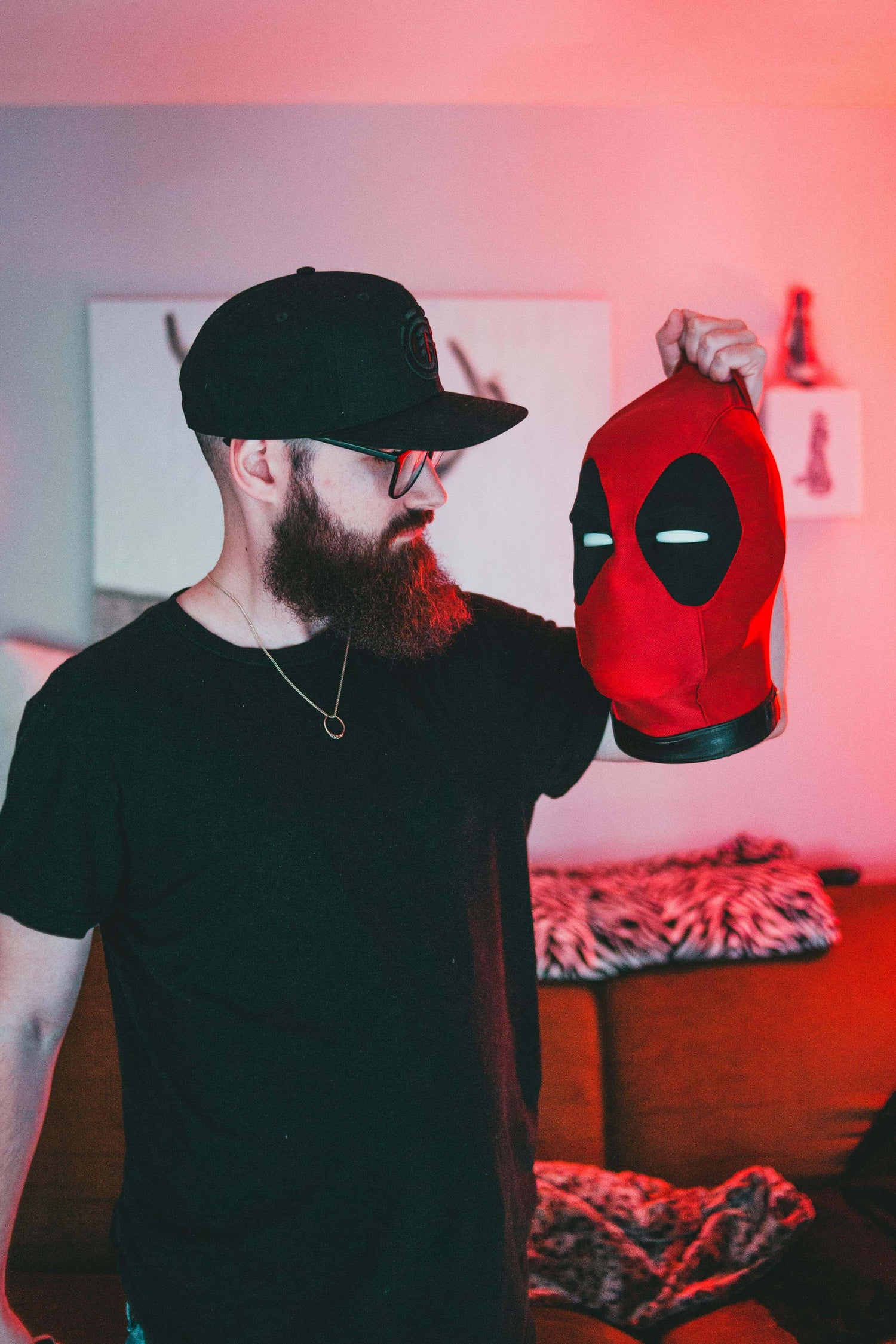 Person with a beard holding a Deadpool mask, representing iconic superhero culture in Marvel movies.