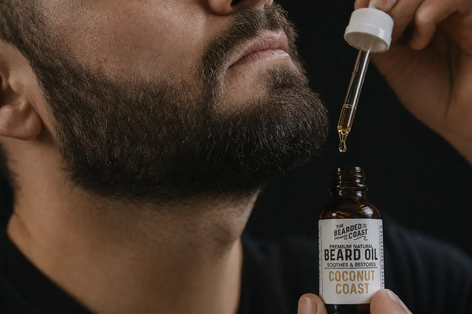 dropping Coconut Coast beard oil into bottle with white cap dropper