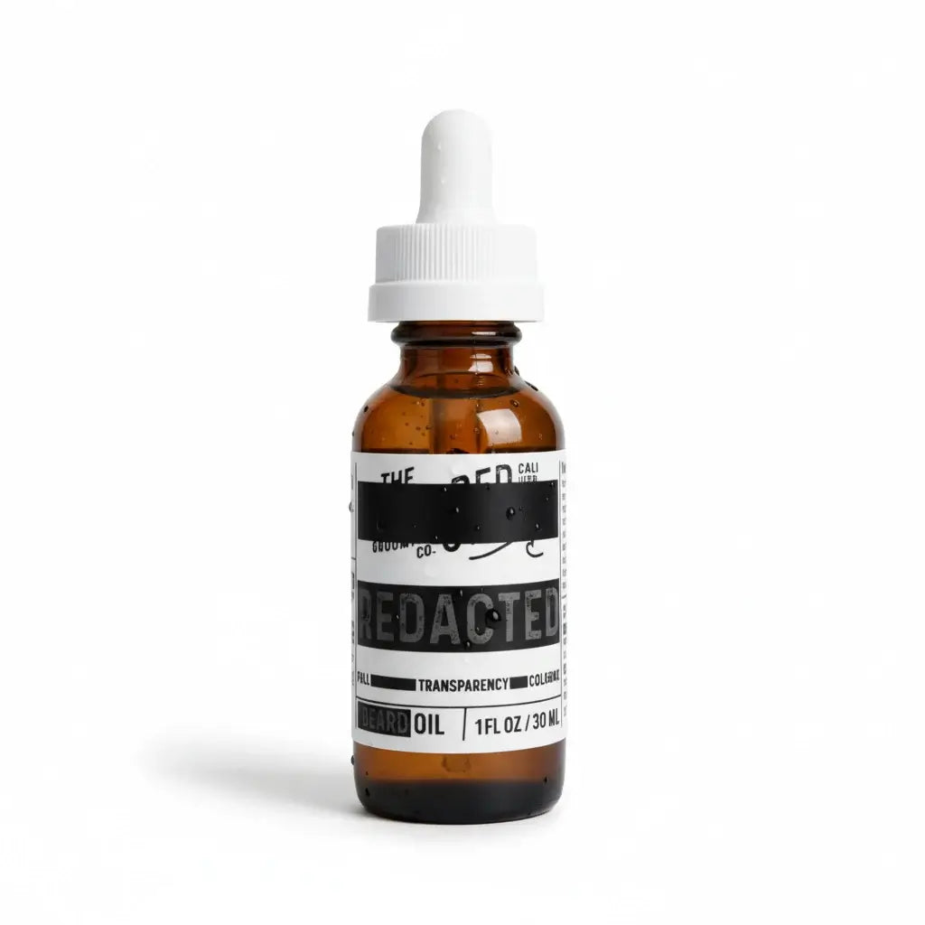 Amber glass dropper bottle labeled “Redacted” beard oil with “Full Transparency Cologne” scent and white cap.