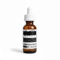 Amber glass dropper bottle labeled “Redacted” beard oil with “Full Transparency Cologne” scent and white cap.