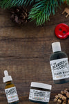 Bearded Coast Pacific Holiday grooming trio with beard oil, butter, and wash on rustic wood with pine and festive accents