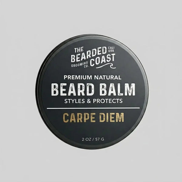Top-down view of The Bearded Coast Grooming Co. Carpe Diem Premium Natural Beard Balm — a 2 oz / 57g dark charcoal metal tin with gold and white typography on a gray background