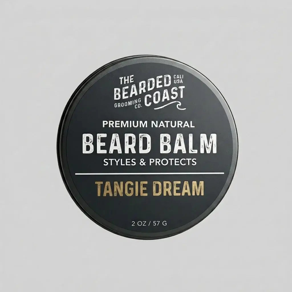 Top-down view of The Bearded Coast Grooming Co. Tangie Dream Premium Natural Beard Balm — a 2 oz / 57g dark charcoal metal tin with gold and white typography on a gray background